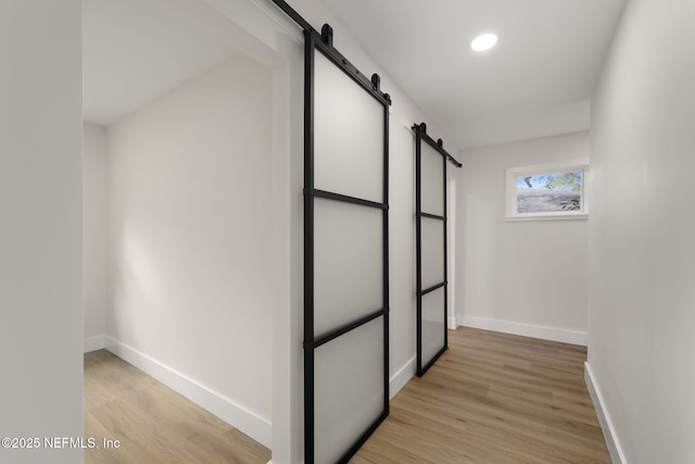 corridor featuring a barn door and light hardwood / wood-style flooring