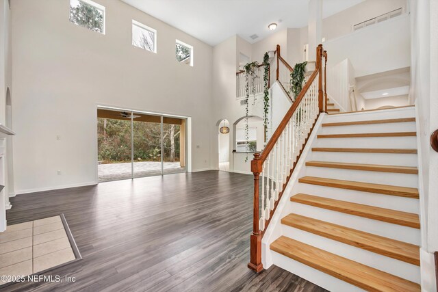 stairway featuring a towering ceiling and wood-type flooring