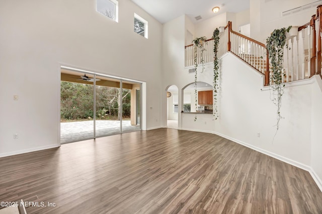 unfurnished living room with wood-type flooring, plenty of natural light, and ceiling fan