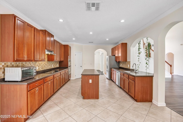 kitchen featuring stainless steel appliances, light tile patterned flooring, a kitchen island, and sink