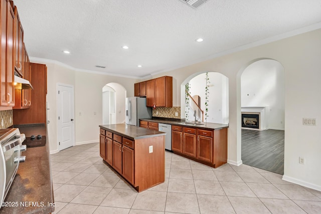 kitchen with light tile patterned flooring, sink, a kitchen island, stainless steel appliances, and backsplash