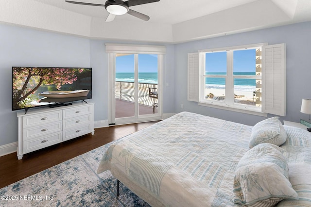 bedroom with ceiling fan, access to exterior, a tray ceiling, and a water view