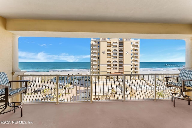 balcony with a water view and a view of the beach