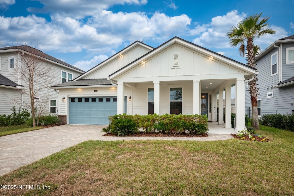 view of front of property with a porch, a front yard, and a garage