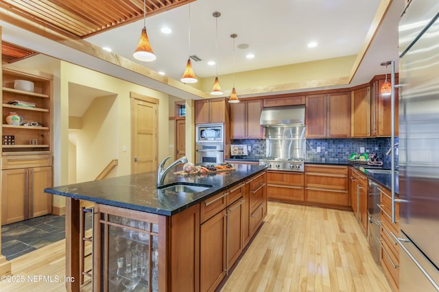 kitchen with appliances with stainless steel finishes, decorative light fixtures, sink, beverage cooler, and a kitchen island with sink