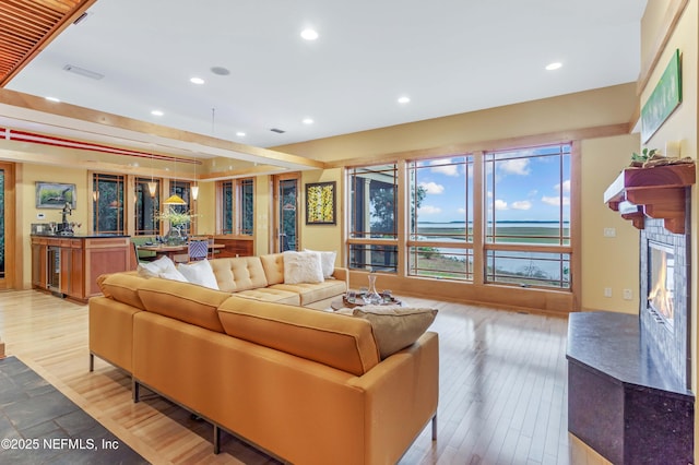 living room with wine cooler, a fireplace, and light wood-type flooring