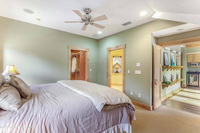 carpeted bedroom featuring ceiling fan, a walk in closet, and beverage cooler