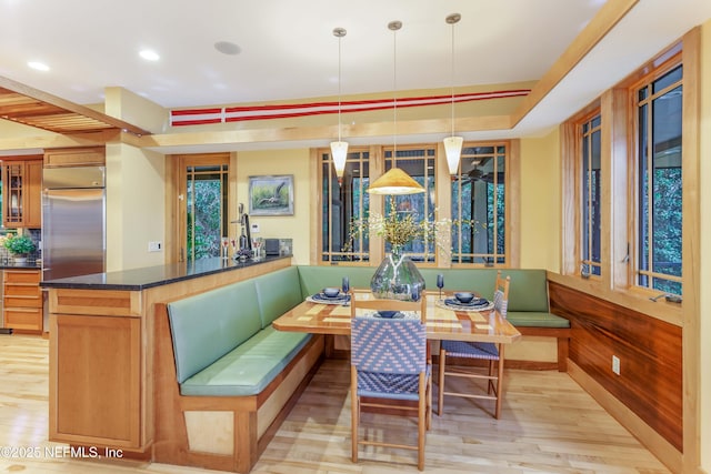 dining room with breakfast area, a tray ceiling, light hardwood / wood-style flooring, and wood walls