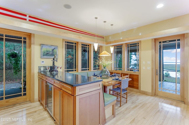 kitchen with pendant lighting, beverage cooler, and light hardwood / wood-style flooring