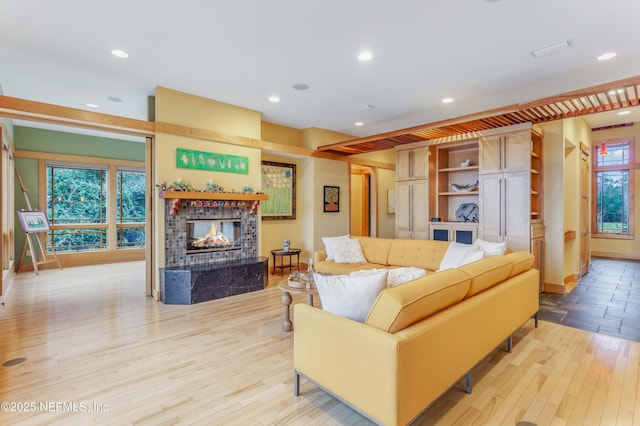 living room with a tile fireplace and light hardwood / wood-style floors