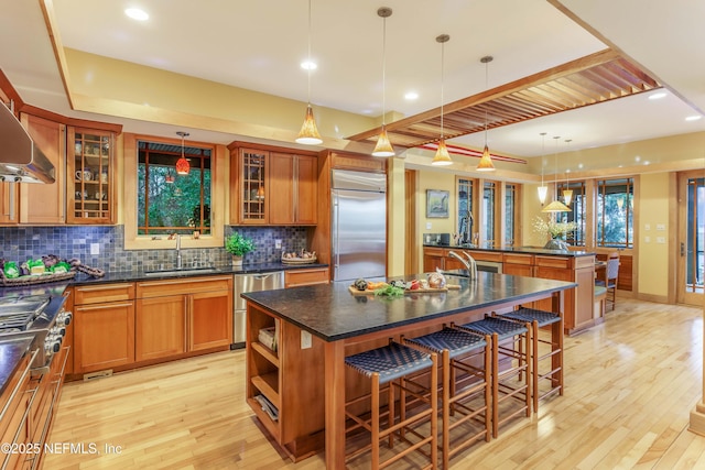 kitchen featuring sink, a breakfast bar, appliances with stainless steel finishes, an island with sink, and decorative light fixtures