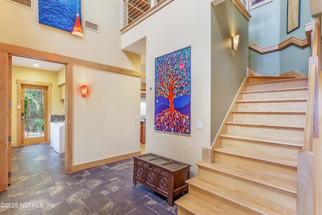 stairs featuring washer / clothes dryer and a high ceiling