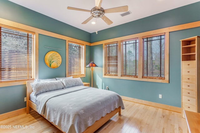 bedroom with multiple windows, hardwood / wood-style floors, and ceiling fan