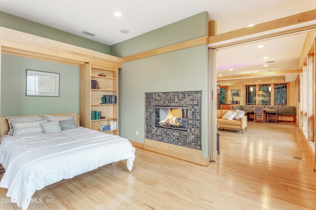 bedroom with a fireplace and light wood-type flooring