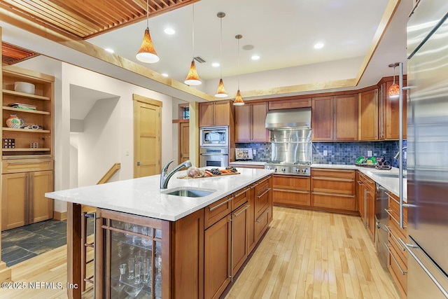 kitchen with pendant lighting, an island with sink, sink, wine cooler, and stainless steel appliances