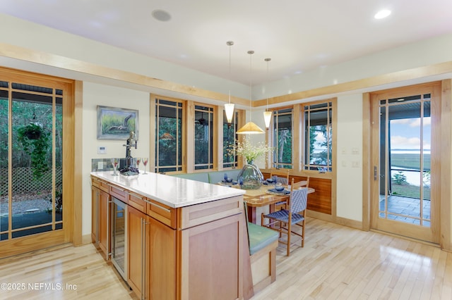 kitchen featuring pendant lighting, beverage cooler, light hardwood / wood-style floors, and kitchen peninsula