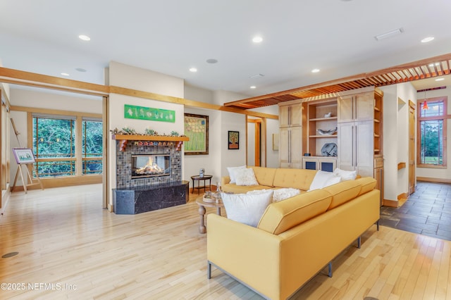 living room with a tiled fireplace and light hardwood / wood-style flooring