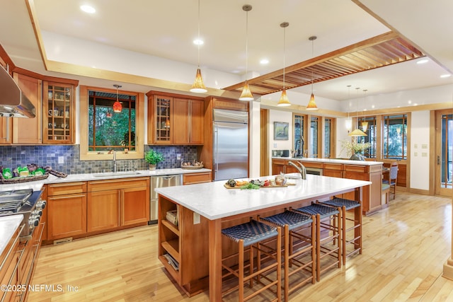 kitchen with sink, a breakfast bar area, appliances with stainless steel finishes, a center island with sink, and decorative light fixtures