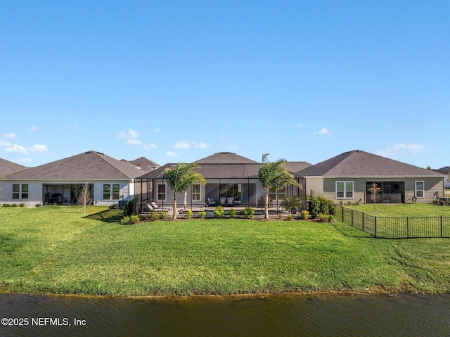 rear view of property featuring a lanai, a lawn, and a water view