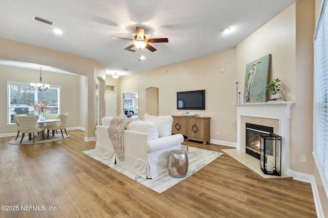 living room with ceiling fan with notable chandelier and light hardwood / wood-style floors