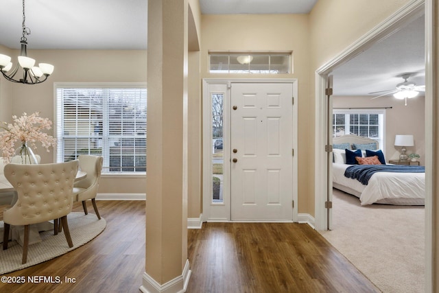 entrance foyer with ceiling fan with notable chandelier and dark hardwood / wood-style floors