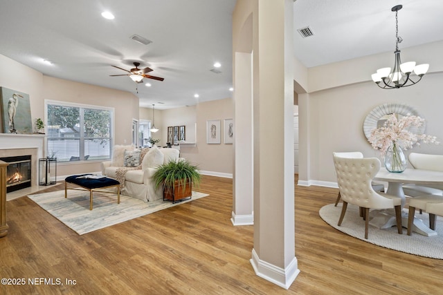 living room with ceiling fan with notable chandelier and light wood-type flooring