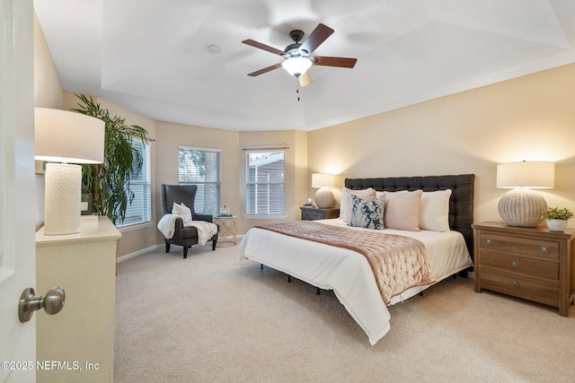 carpeted bedroom featuring a raised ceiling and ceiling fan