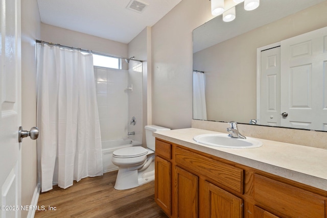 full bathroom with hardwood / wood-style floors, vanity, toilet, and shower / tub combo with curtain