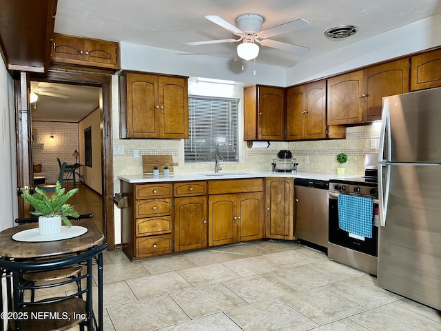 kitchen featuring ceiling fan, sink, backsplash, and stainless steel appliances