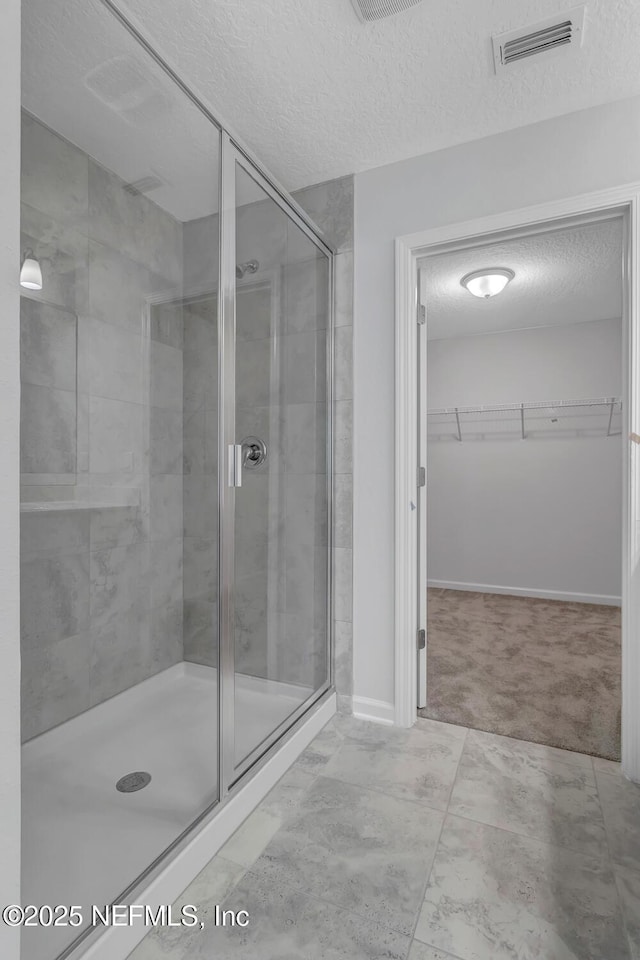 bathroom featuring a shower with door and a textured ceiling