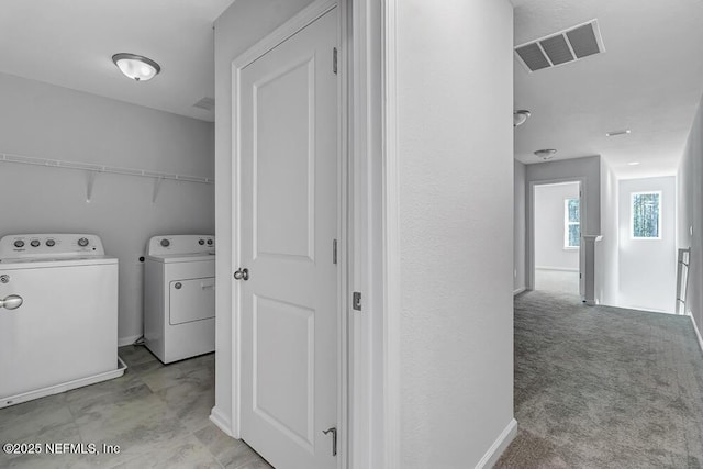 clothes washing area with separate washer and dryer and light carpet