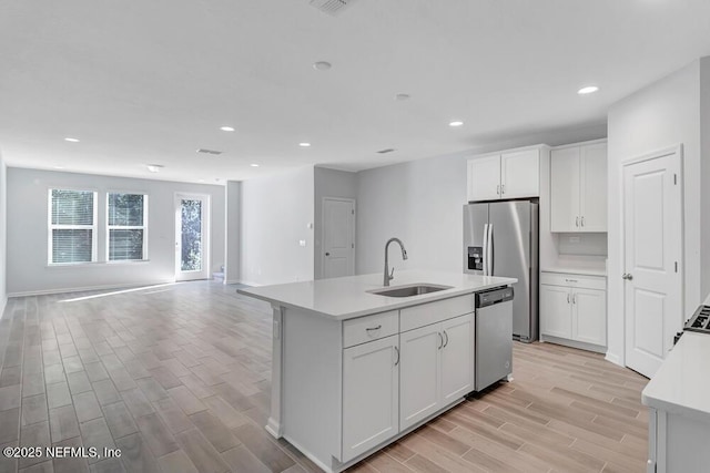 kitchen featuring a kitchen island with sink, sink, white cabinets, and appliances with stainless steel finishes