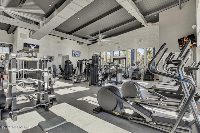 gym featuring brick wall and high vaulted ceiling