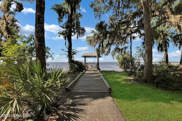 view of dock with a yard and a water view