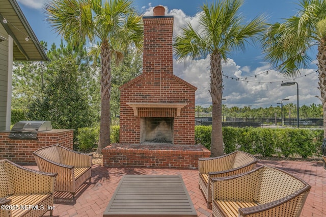 view of patio featuring an outdoor kitchen, an outdoor brick fireplace, and a grill