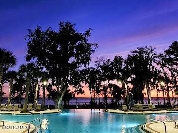 pool at dusk featuring a patio