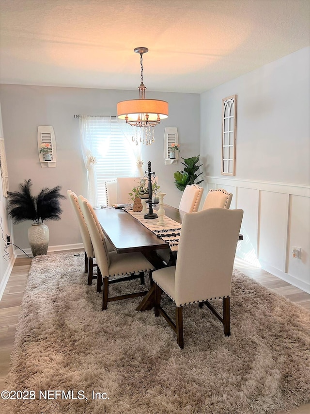 dining space with hardwood / wood-style floors and a notable chandelier