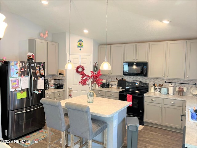 kitchen featuring backsplash, gray cabinetry, vaulted ceiling, black appliances, and decorative light fixtures