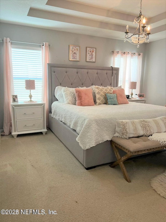 bedroom with a raised ceiling, carpet floors, multiple windows, and a chandelier