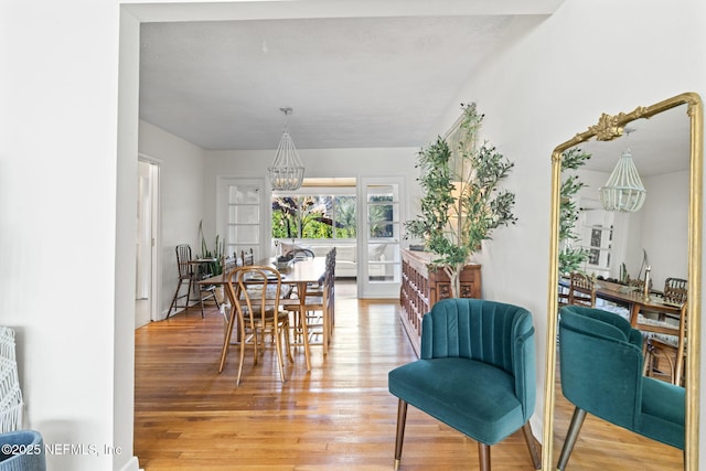 dining space with hardwood / wood-style floors and a notable chandelier