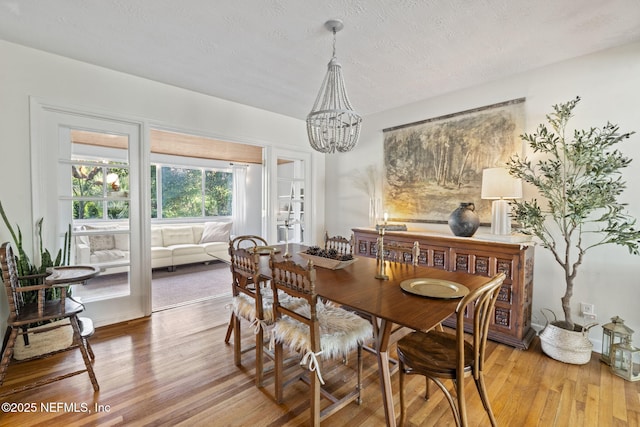 dining room featuring an inviting chandelier, a textured ceiling, and light hardwood / wood-style floors