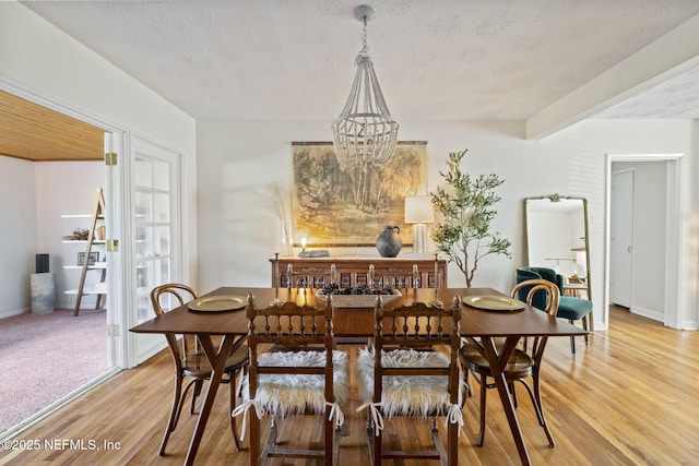 dining room with an inviting chandelier, hardwood / wood-style floors, beam ceiling, and a textured ceiling