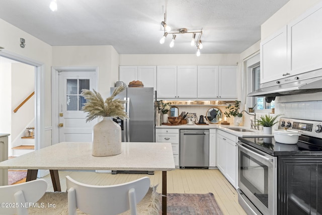 kitchen with tasteful backsplash, white cabinetry, appliances with stainless steel finishes, and sink