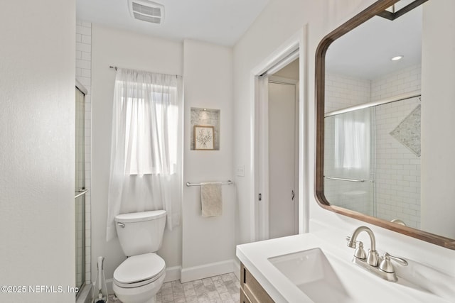 bathroom featuring vanity, a shower with door, and toilet