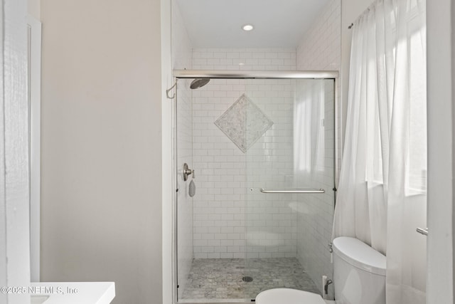 bathroom with a shower with door and toilet