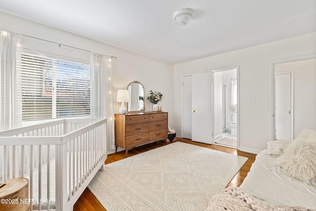 bedroom with ensuite bath and hardwood / wood-style floors