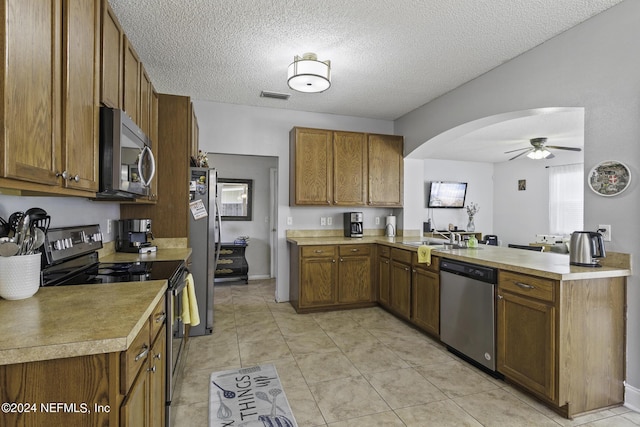 kitchen featuring light tile patterned flooring, ceiling fan, kitchen peninsula, stainless steel appliances, and a textured ceiling