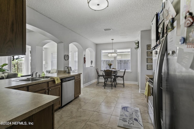 kitchen with sink, dark brown cabinets, stainless steel appliances, and hanging light fixtures