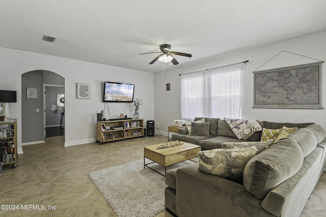 living room with a textured ceiling, ceiling fan, and light tile patterned flooring