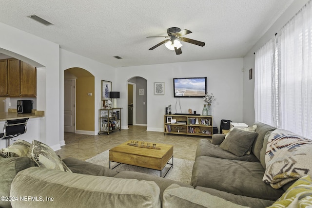 living room featuring ceiling fan, a textured ceiling, and light tile patterned floors